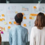 Séance de brainstorming en équipe avec un tableau blanc rempli de graphiques et de post-it, bureau moderne et propre